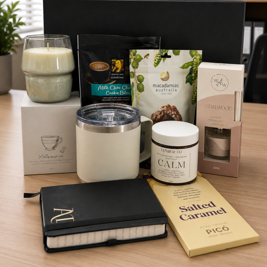 Collection of items including a candle, coffee package, and a notebook on a wooden surface.