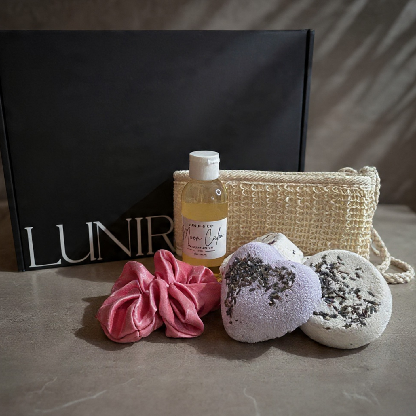 Bottle of 'Lumin & Co' oil, pink candle, and textured soap dish on a windowsill.