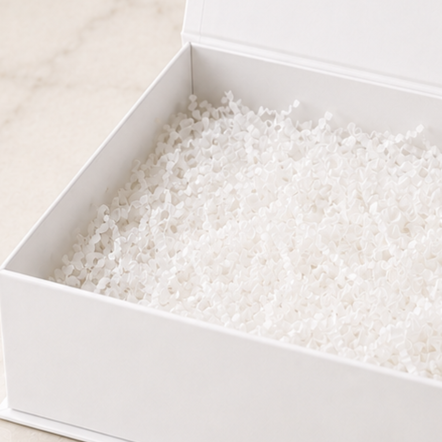 White beads in a white box on a light beige background