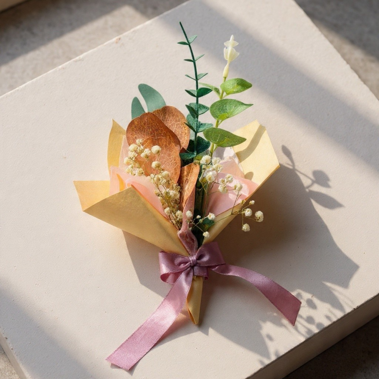 Small bouquet with pink ribbon on a light surface