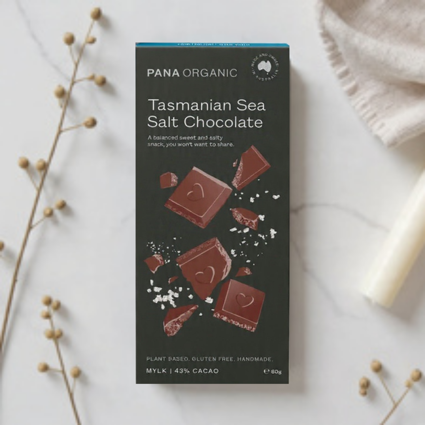 Pana Organic Tasmanian Sea Salt Chocolate packaging on a marble surface with decorative elements.