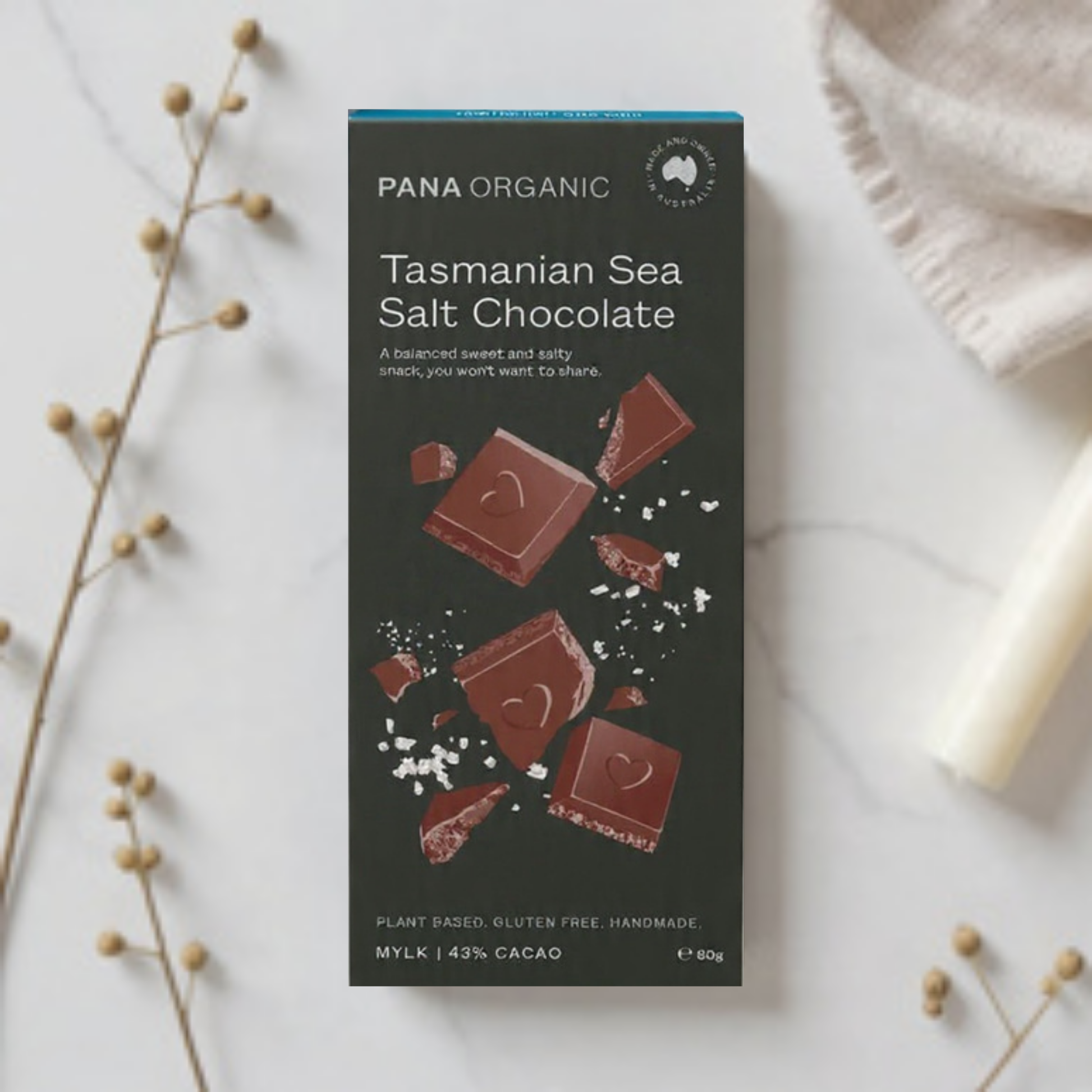 Pana Organic Tasmanian Sea Salt Chocolate packaging on a marble surface with decorative elements.