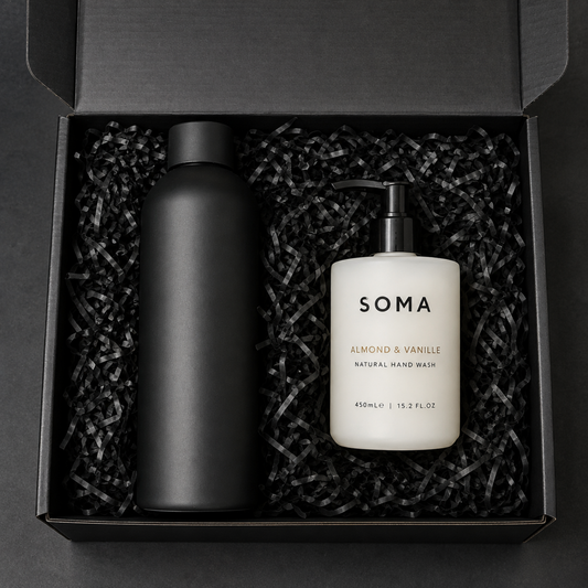 SOMA Almond & Vanille natural hand wash gift set in a black box with black crinkle paper. The set includes a matte black bottle and a white pump bottle with black text.