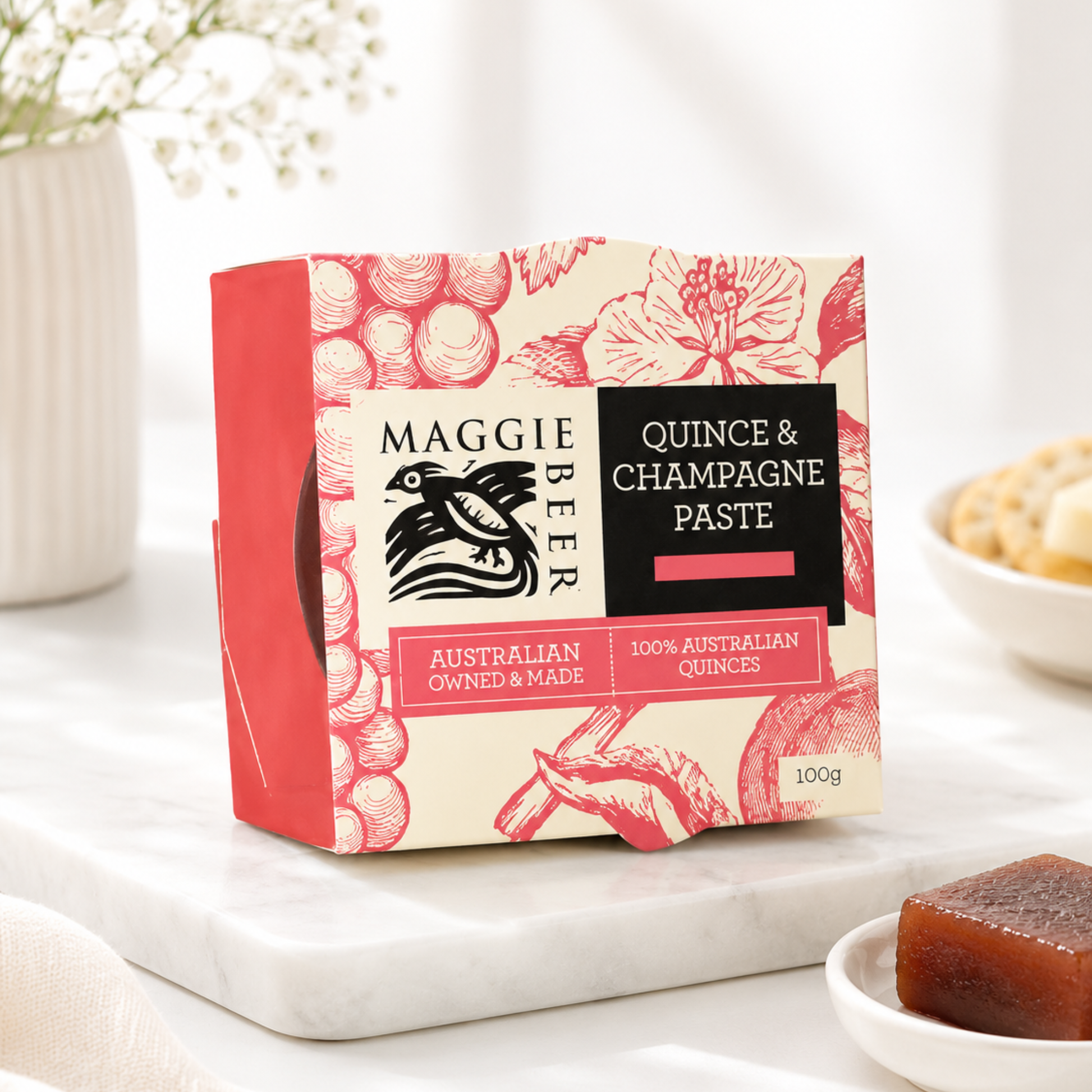 Maggie Beer Quince & Champagne Paste packaging on a marble surface with a bowl of cookies.