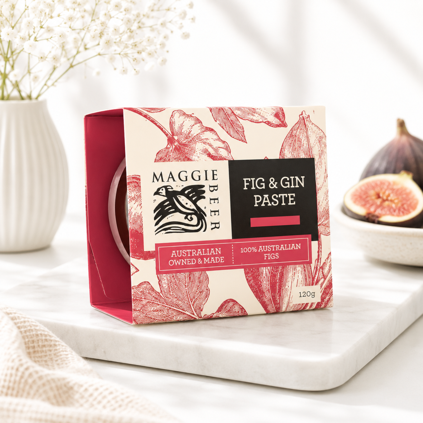 Maggie Beer Fig & Gin Paste packaging on a white surface with figs and flowers in the background