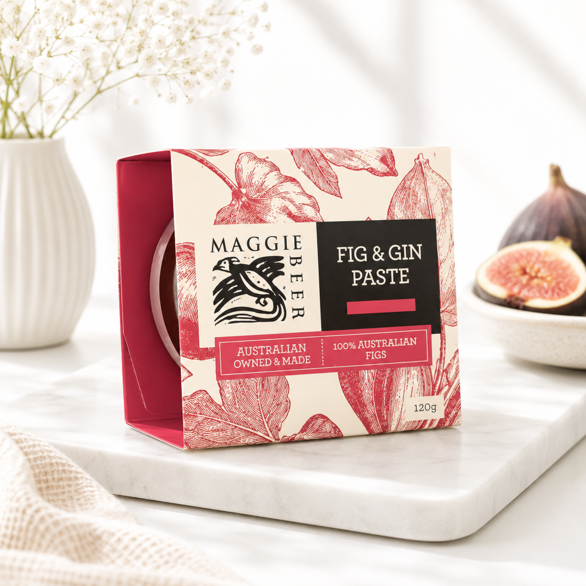 Maggie Beer Fig & Gin Paste packaging on a white surface with figs and flowers in the background