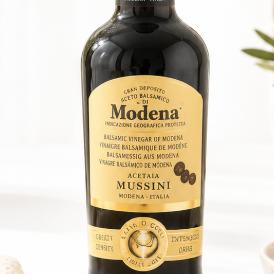 Bottle of Modena balsamic vinegar with a gold label on a white background