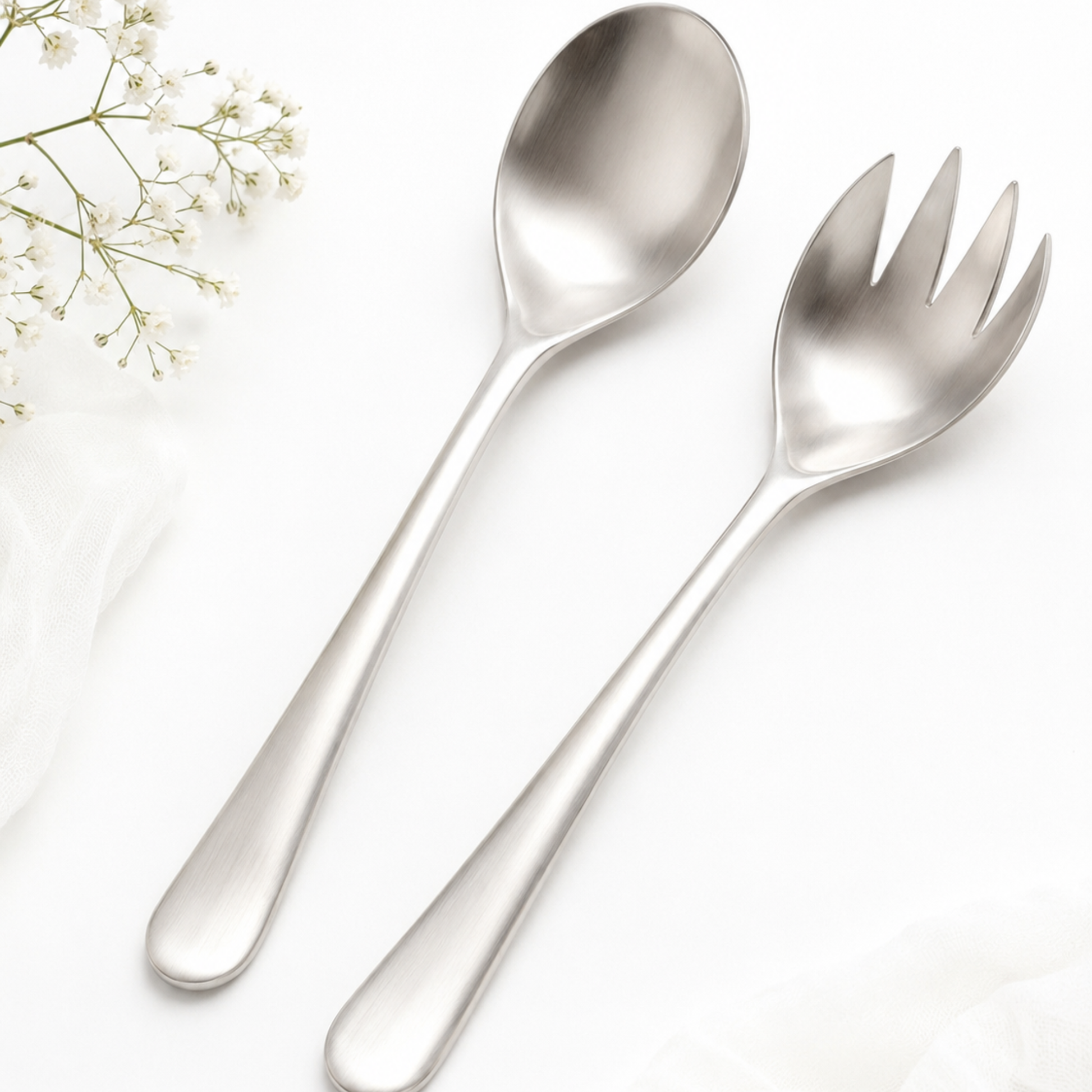 Stainless steel spoon and fork set on a white background with small flowers.