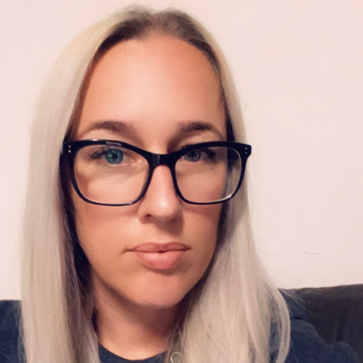 Person with glasses and blonde hair against a plain background