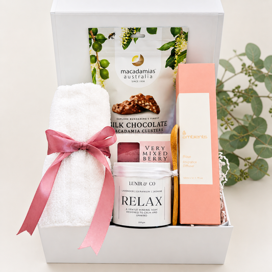 Gift basket with towel, chocolate, candle, and soap on a white background