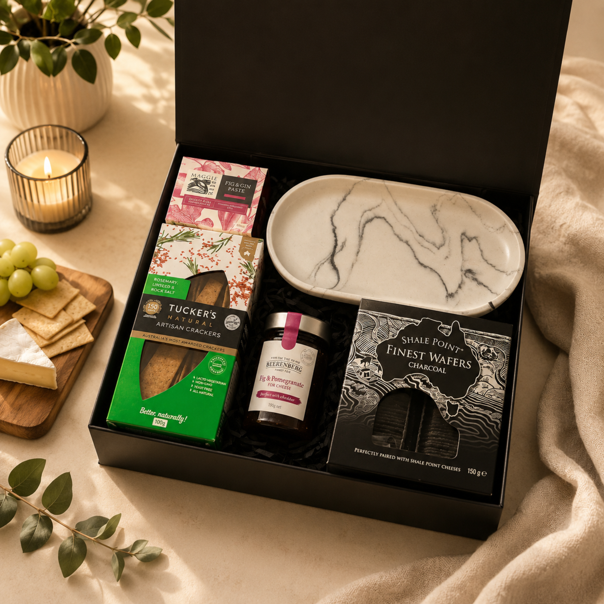 Gourmet gift box with snacks and a marble-patterned plate on a decorative table.