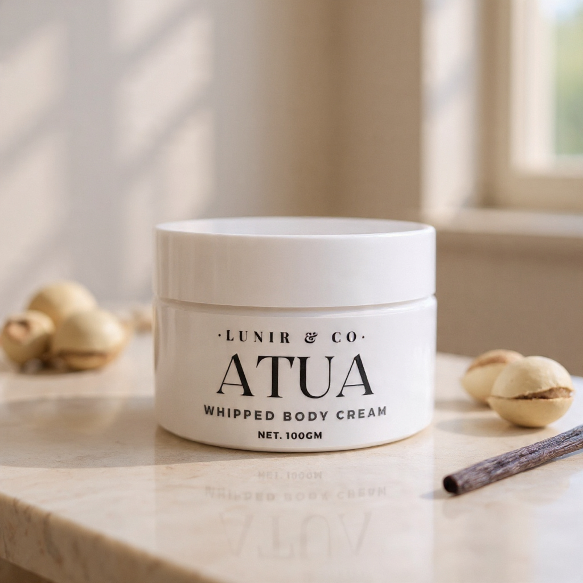 White jar of ATUA whipped body cream on a marble surface with neutral background