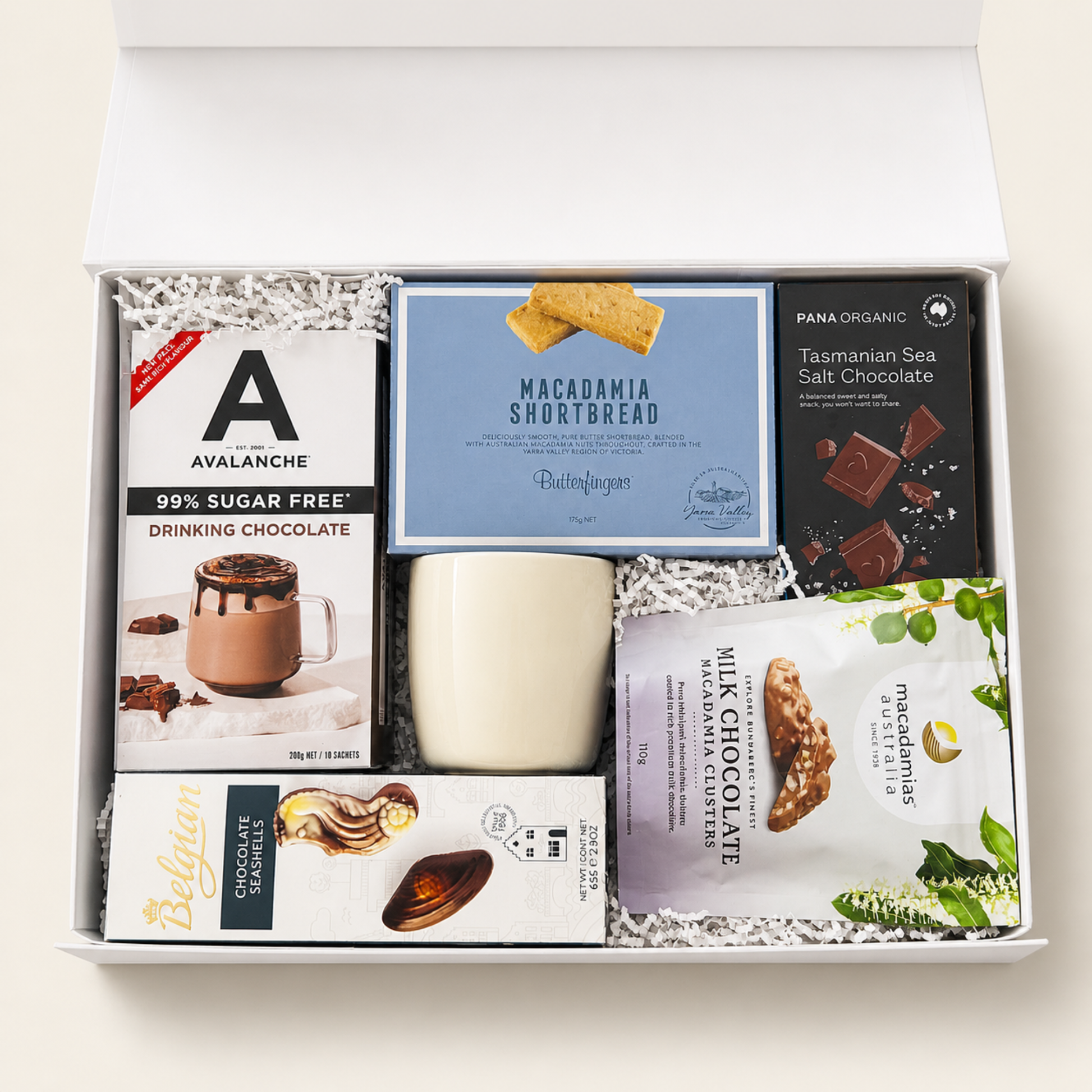 Gift box with assorted snacks including chocolate and cookies on a light background