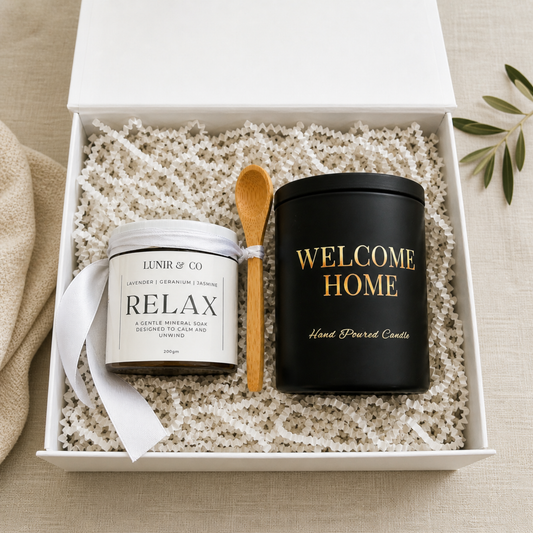 Two candles and a wooden spoon in a decorative box on a textured surface.