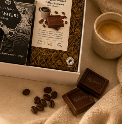 Whittaker's chocolate bars with coffee beans and a cup of coffee on a beige surface