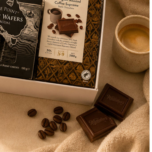 Whittaker's chocolate bars with coffee beans and a cup of coffee on a beige surface