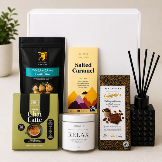 Assorted food and coffee products on a white surface with a plant in the background