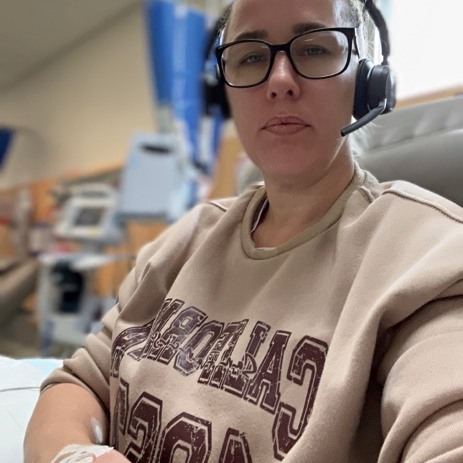 Person wearing a headset and beige sweatshirt with text in a hospital setting