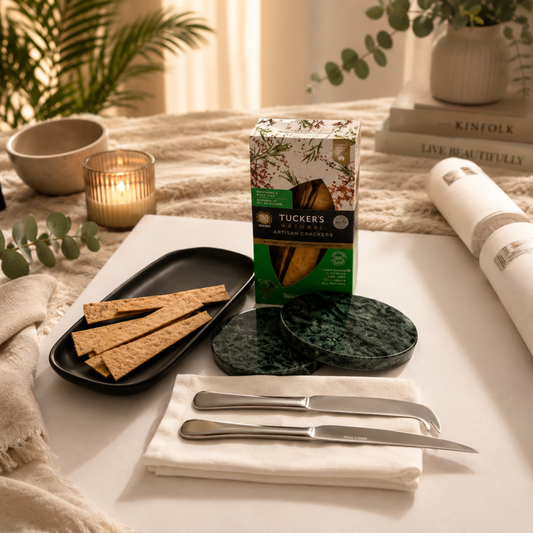 Table setting with crackers, a box of Tucker's chocolate, and cutlery on a white tablecloth.