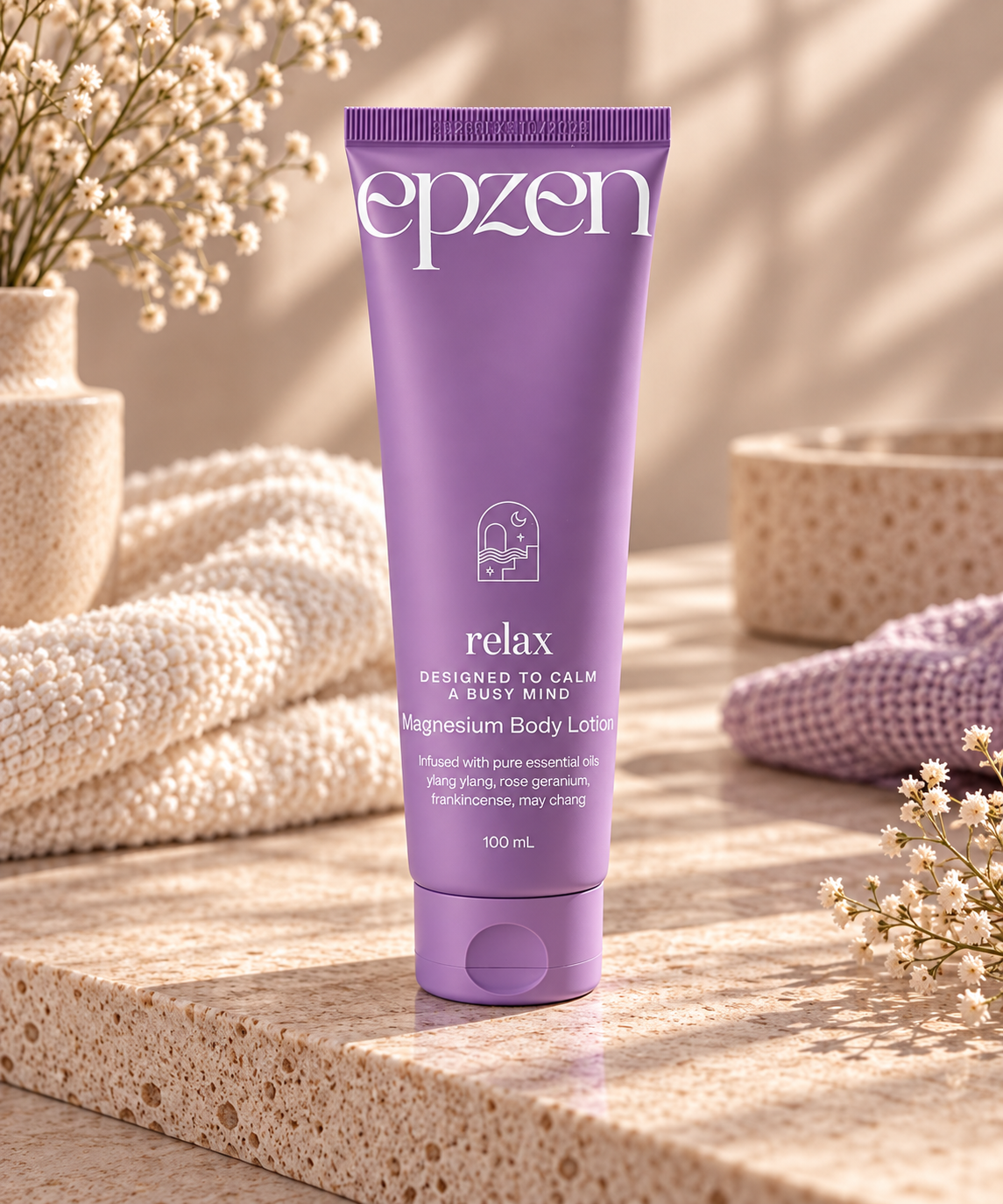 A 100 mL tube of epzen Relax Magnesium Body Lotion standing on a textured stone surface, surrounded by cozy knitted blankets, dried flowers, and warm natural light.