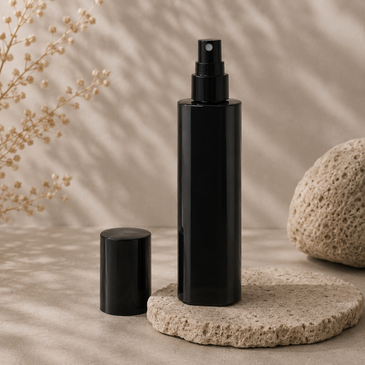 Black spray bottle and cylindrical container on a stone surface with a natural background