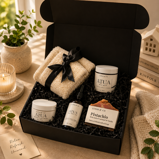 Gifting set with bath products and towel in a black box on a soft surface.