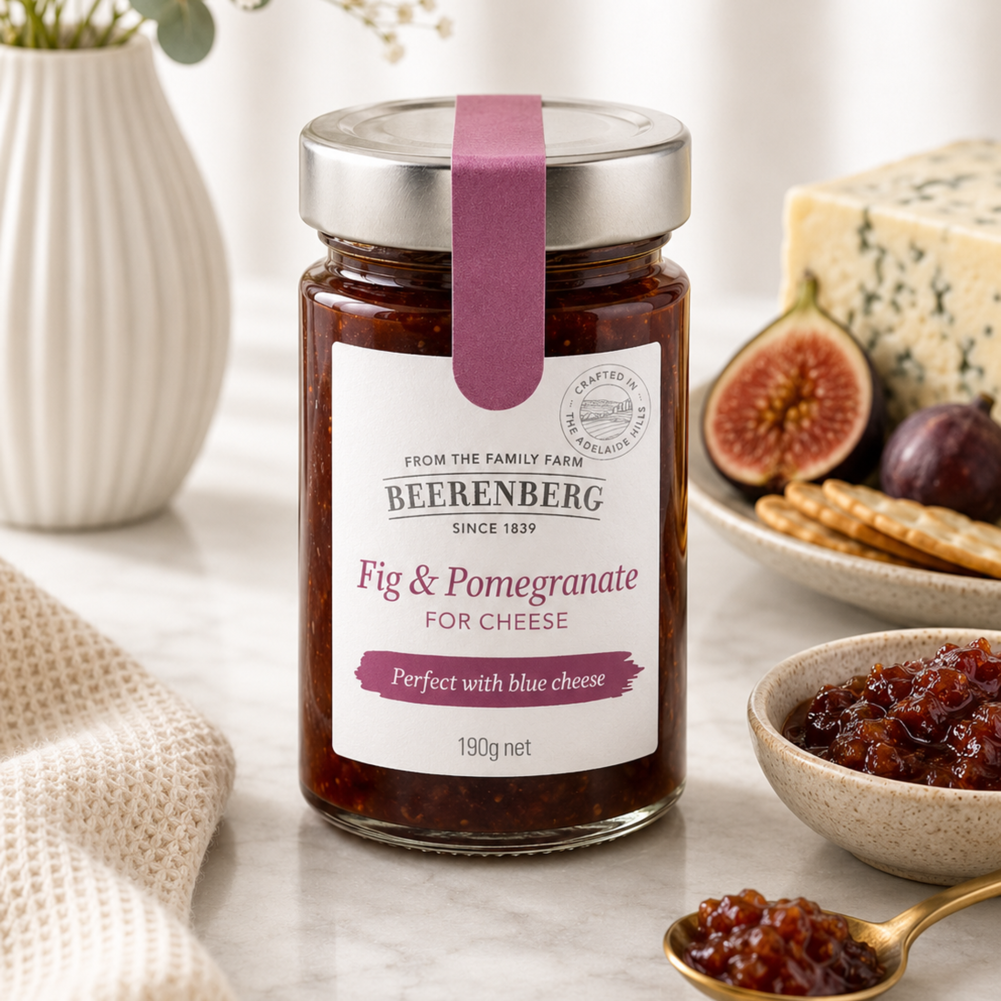 Jar of Beerenberg Fig & Pomegranate for Cheese on a table with figs, crackers, and cheese.