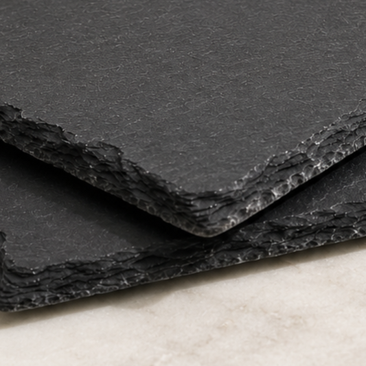 Stack of black textured paper sheets on a light surface