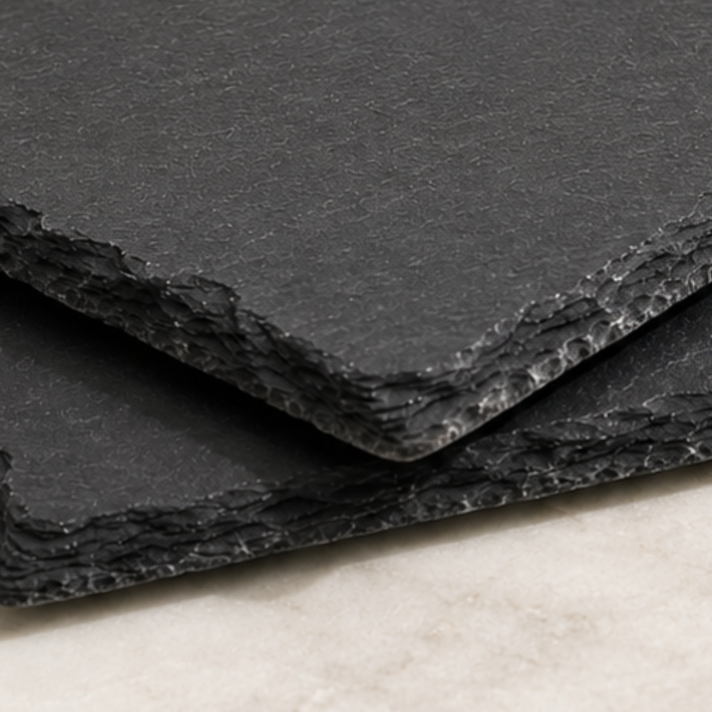 Stack of black textured paper sheets on a light surface