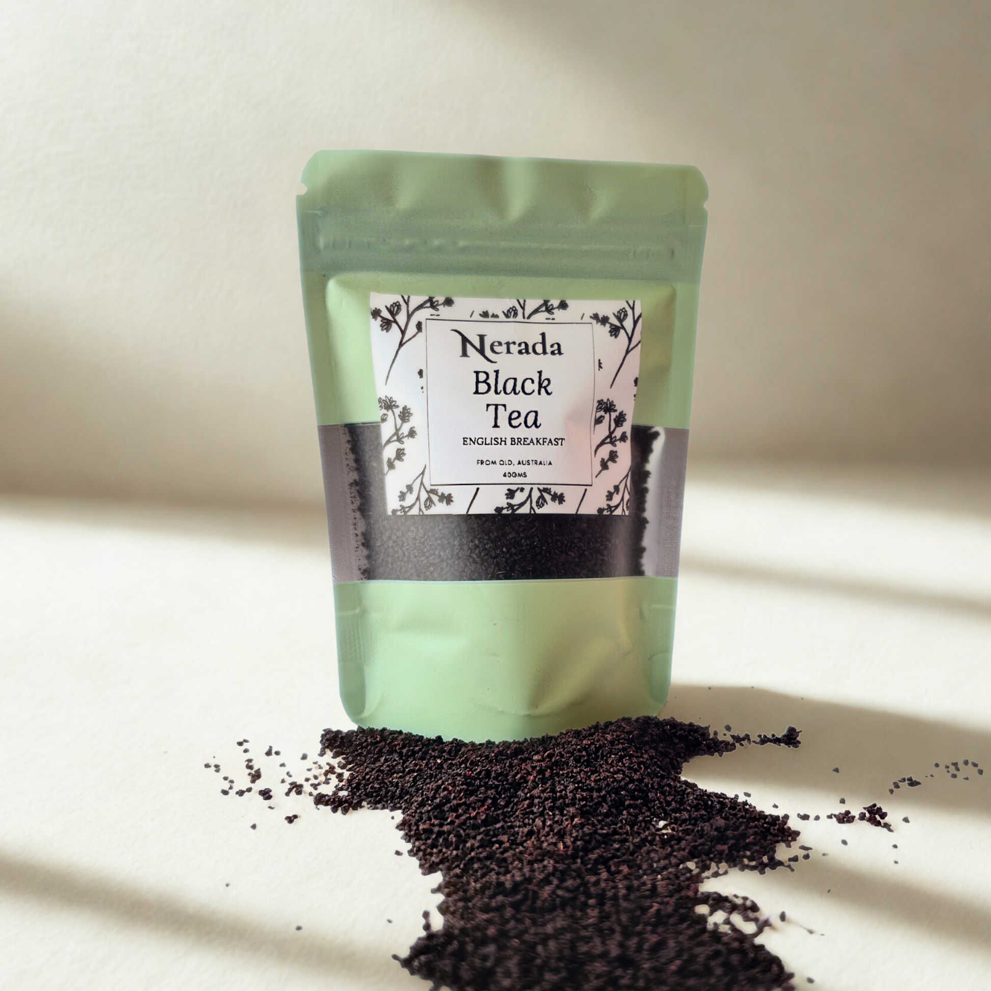 Green package of Nerada Black Tea with scattered tea leaves on a light background