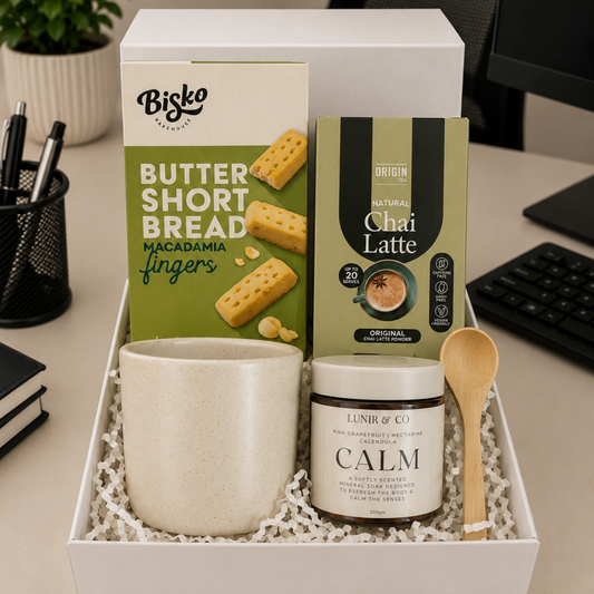 Gift set with Bisko butter shortbread, Chai Latte tea, and Calm product in a box on a desk.