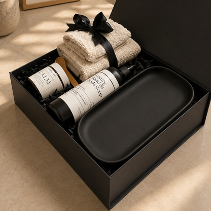 Gift set with towels, bottles, and a tray in a black box on a beige surface