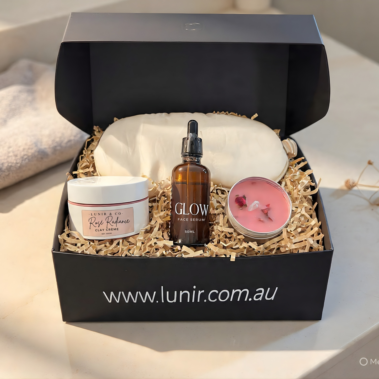 Glowing skincare product set with a candle and face mask in a black box, featuring the brand 'Lunir'.