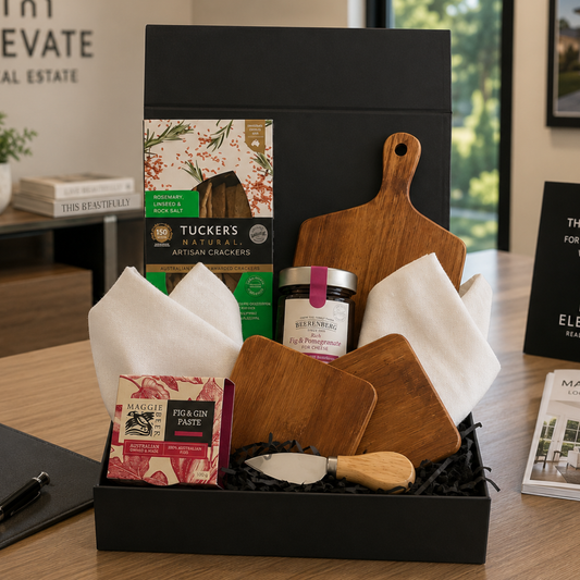 Gift basket with cutting boards, jars, and other items on a table.