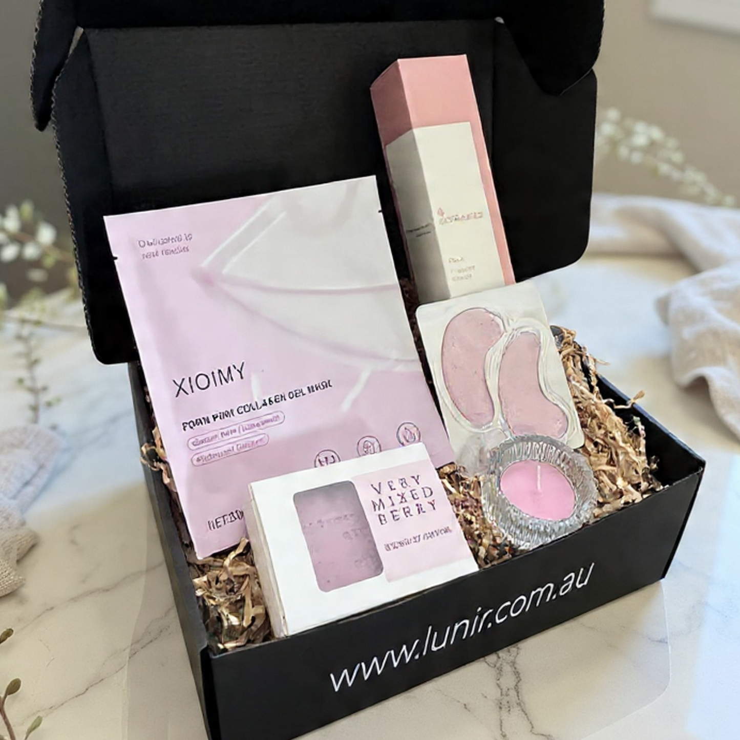 Gift box with skincare products and a candle on a marble surface