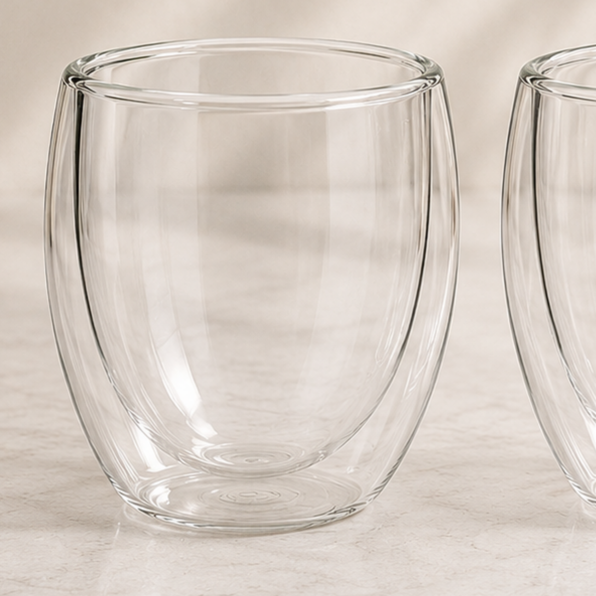Two clear glass tumblers on a light wooden surface