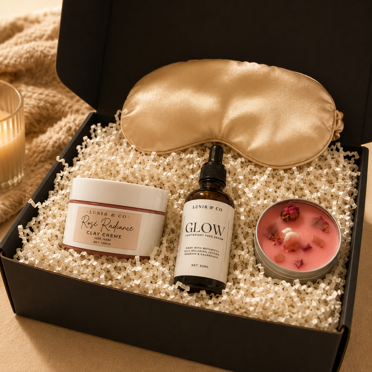 Skincare and wellness gift set with eye mask, cream, serum, and candle in a box.