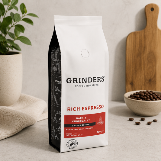 Grinders Coffee Roasters Rich Espresso package on a neutral background with coffee beans and a plant.