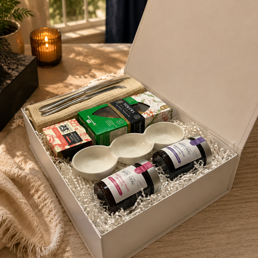 Gift set with tea, oils, and ceramic items on a wooden surface.
