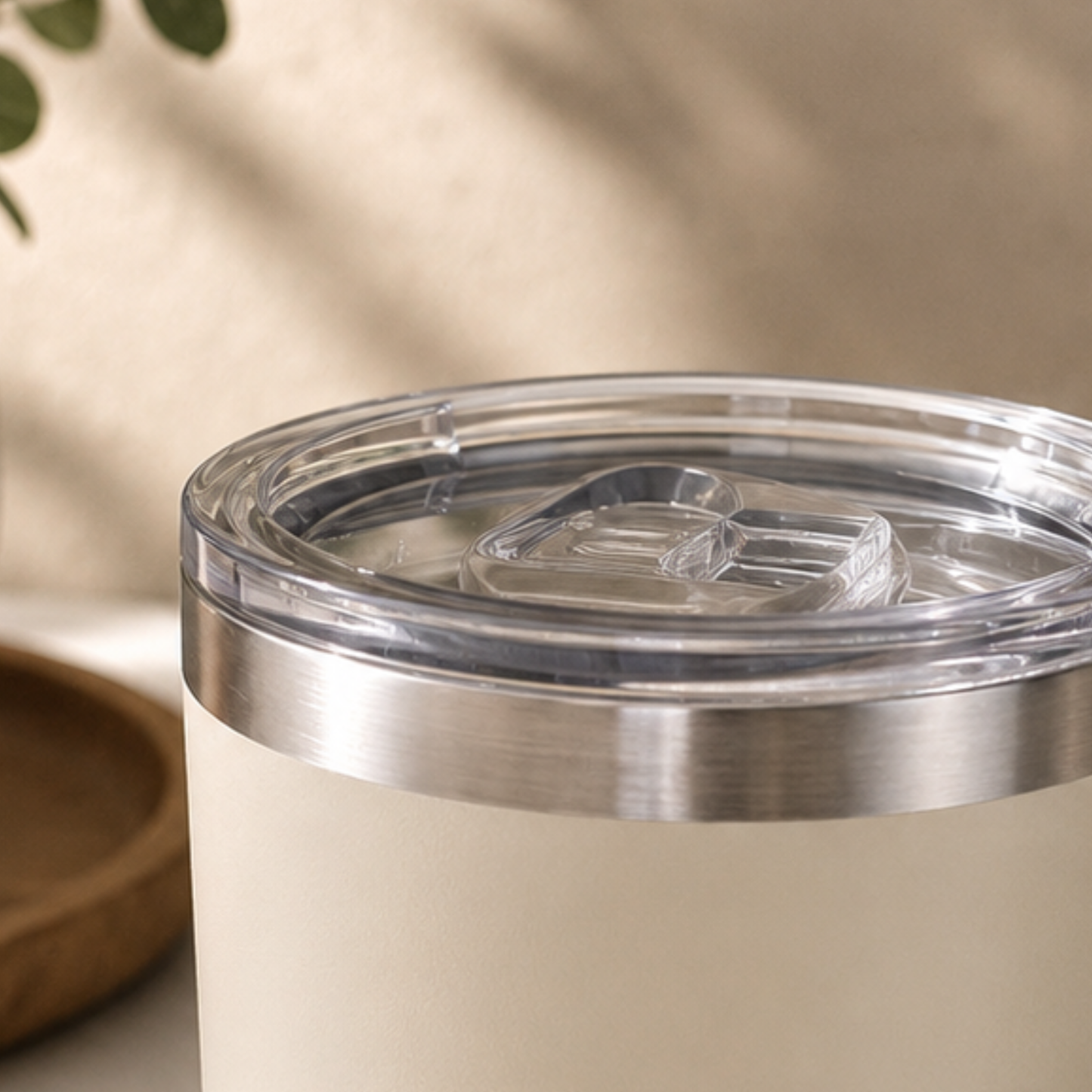 Close-up of a beige tumbler with a clear lid on a neutral background