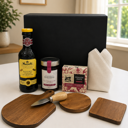 Gourmet gift set with bottles, wooden boards, and a knife on a table.