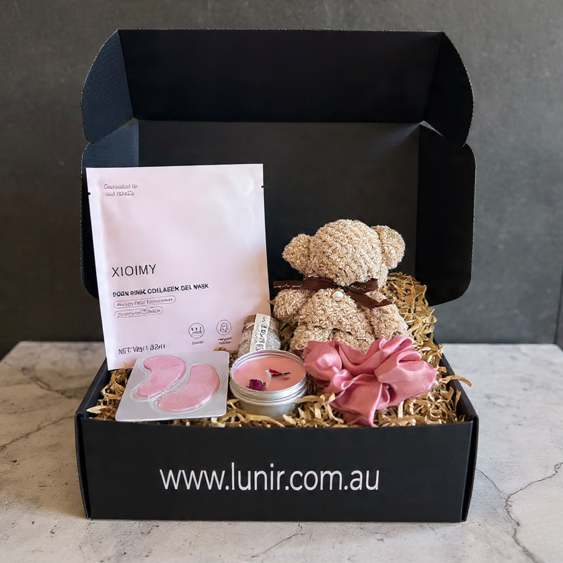 Bath products including a bottle, pink towel, and bath bombs in front of a black box labeled 'LUNIR'.
