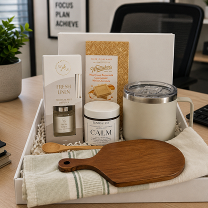 Gift tray with various items including a mug, candles, and a cutting board on a desk.