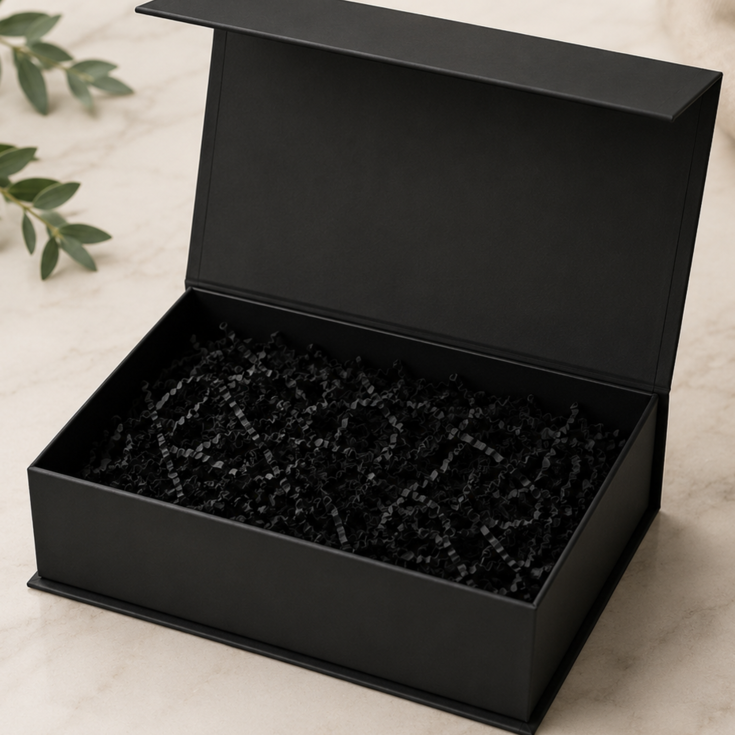 Black jewelry box with black interior on a light beige surface