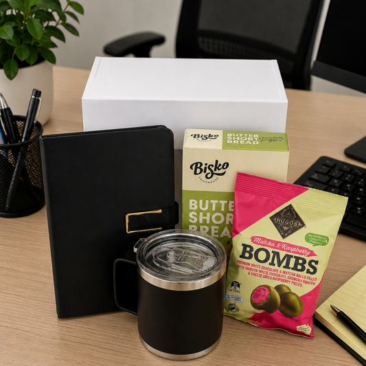 Desk setup with a black mug, notebook, and various snacks in an office setting