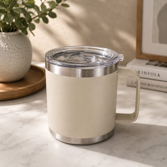 Beige mug with a clear lid on a marble surface, with a plant and books in the background.