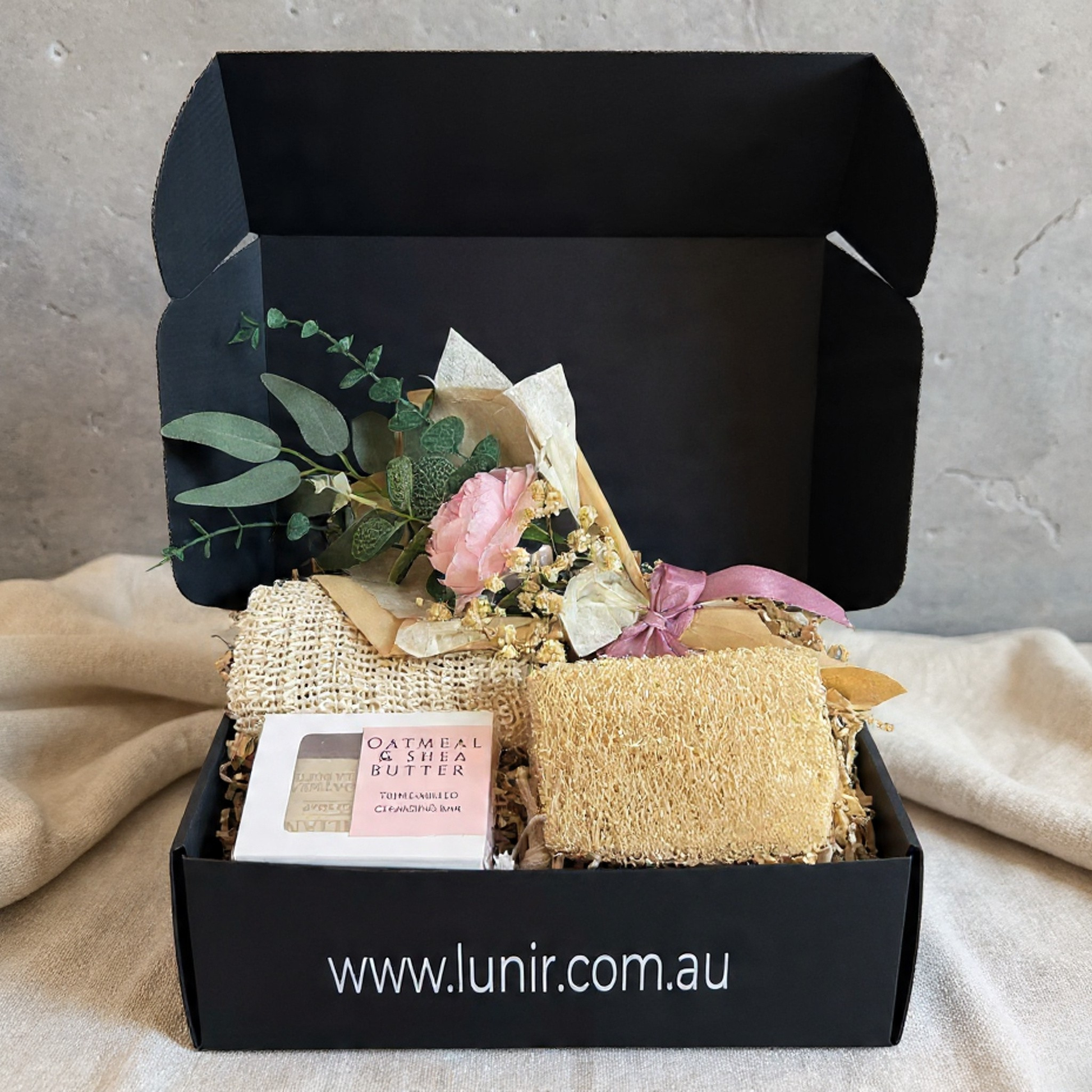 Gift box with bath products and flowers on a neutral background