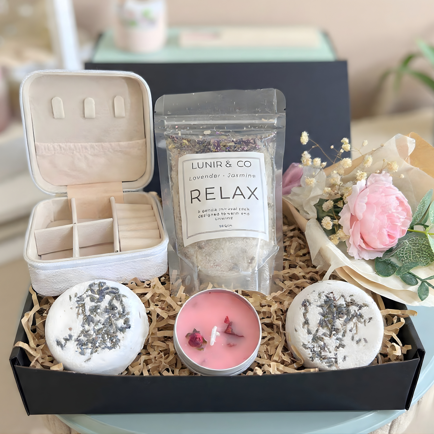 Gift box with teddy bear, pink items, and a product package on a neutral background