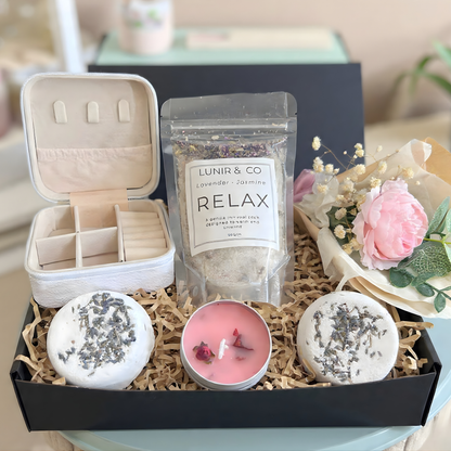 Gift box with teddy bear, pink items, and a product package on a neutral background