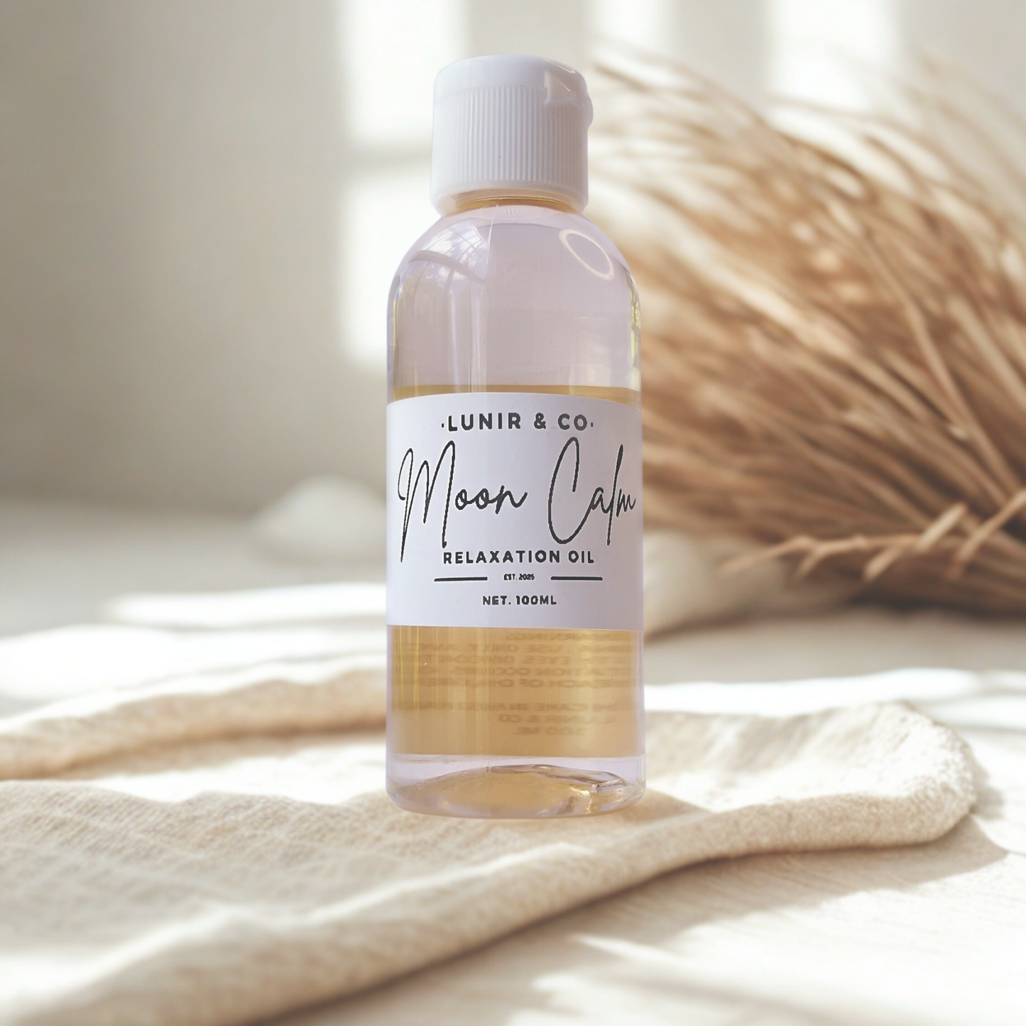 Bottle of 'Moon Calm' relaxation oil by Lunir & Co. on a light fabric background